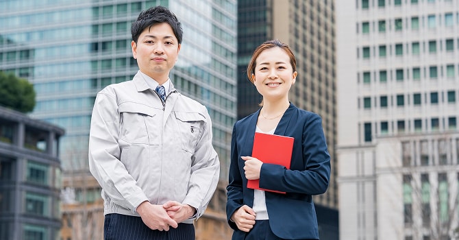 仕事中の男女がこちらを向いて微笑むイメージ写真